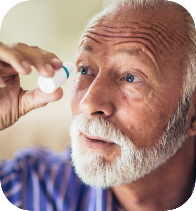 older man putting eye drops in